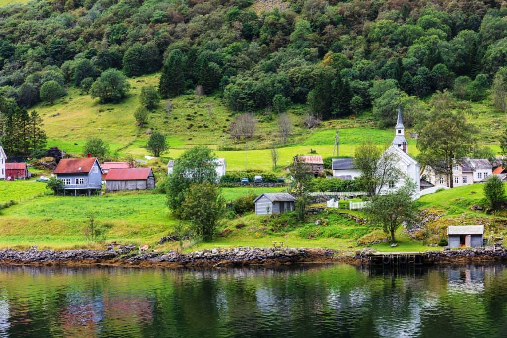 Huizen en een kerk aan de oever in de Geirangerfjord, Noorwegen