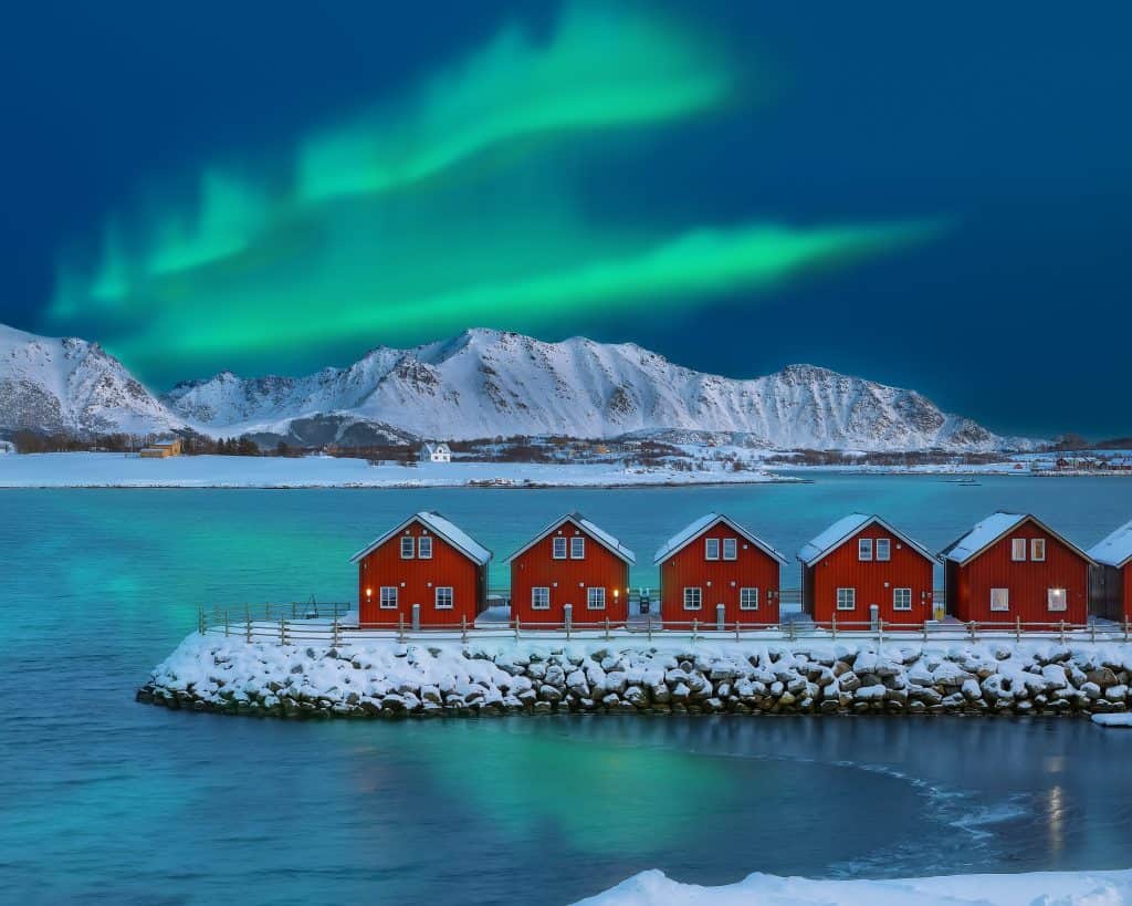 Noorderlicht en traditionele rode houten huizen in Noorwegen